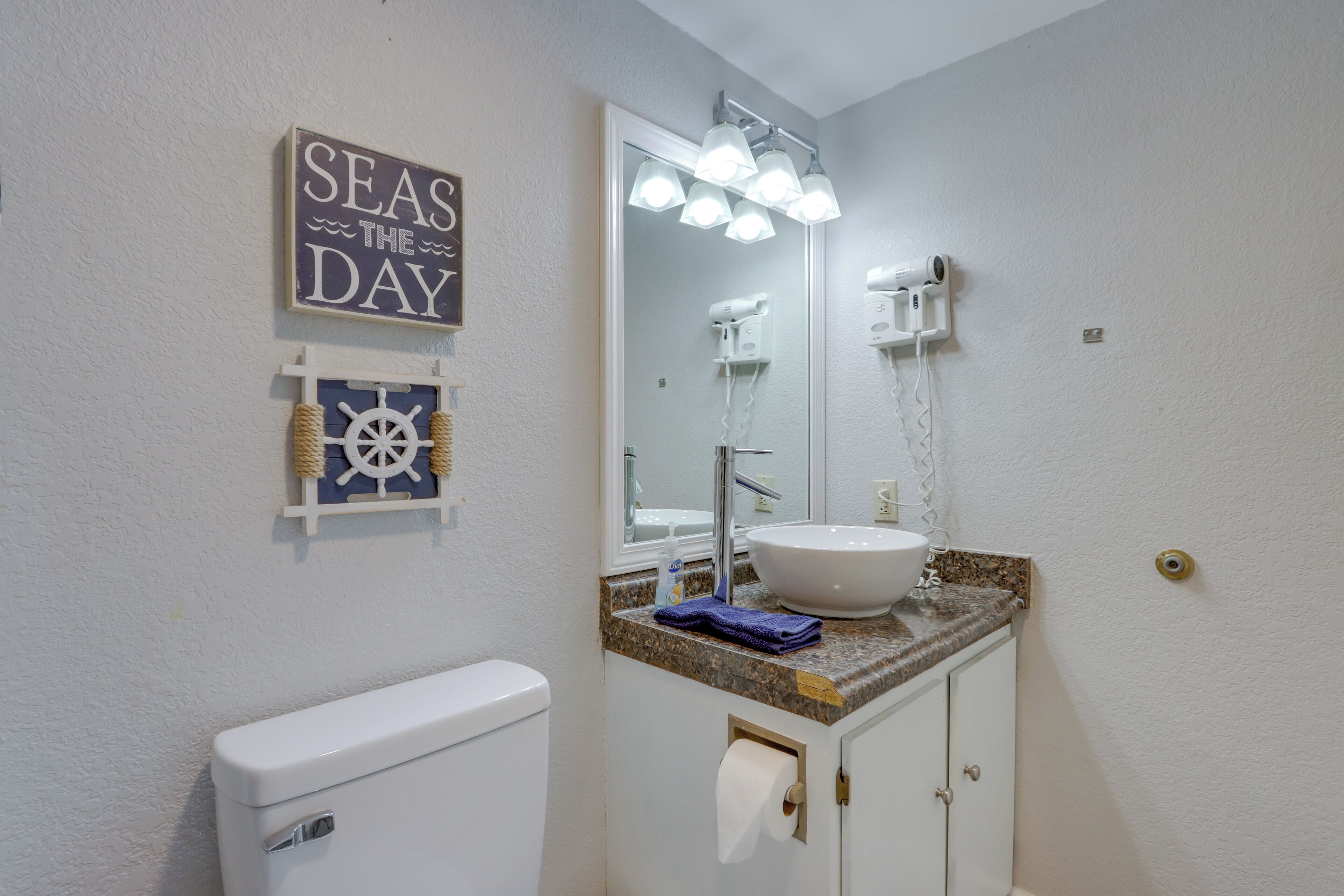 Ein Badezimmer mit Toilette, Waschbecken mit Spiegel und Handtuchhalter.