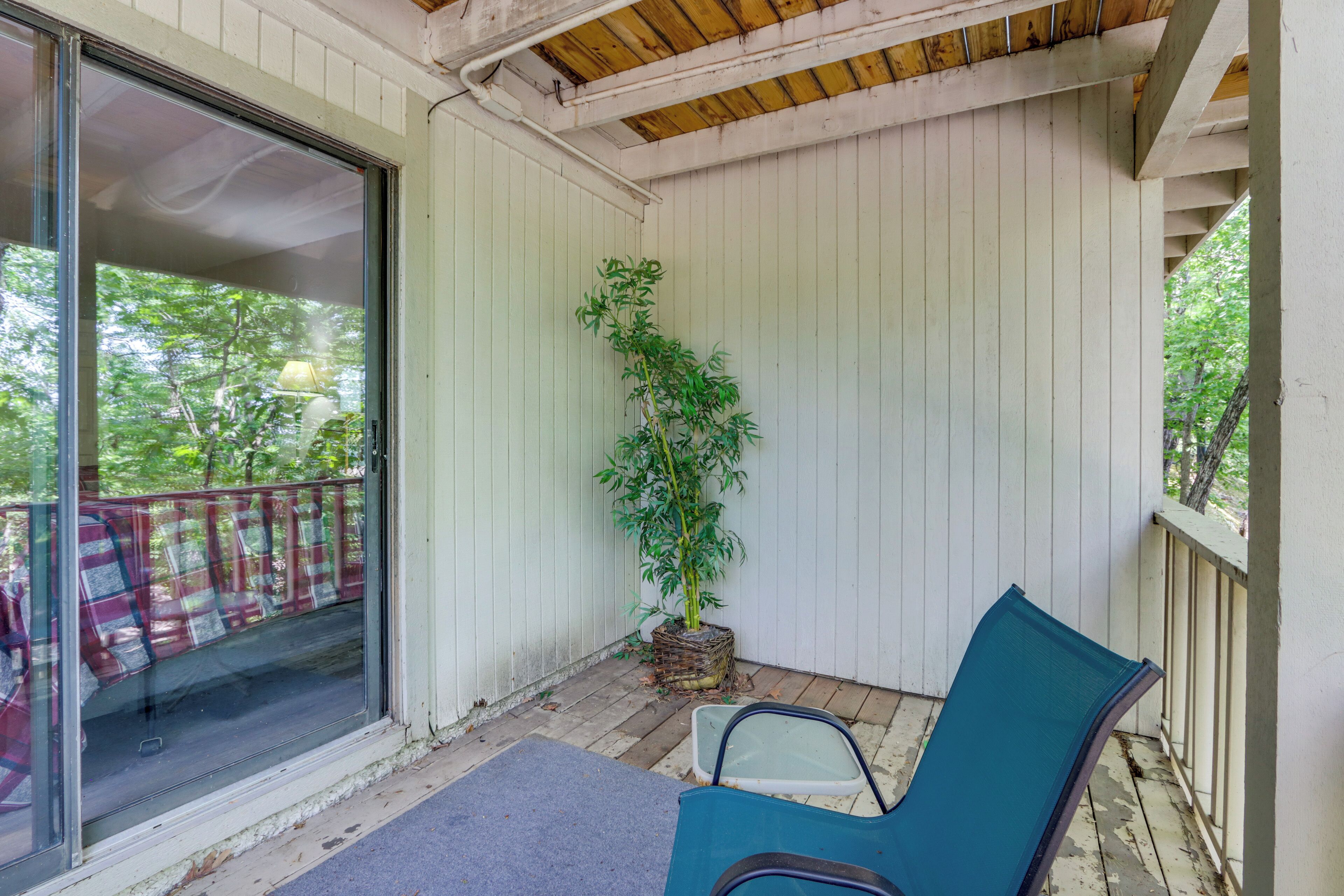 Un porche abrité avec une porte-fenêtre coulissante, une plante en pot et une chaise bleue.