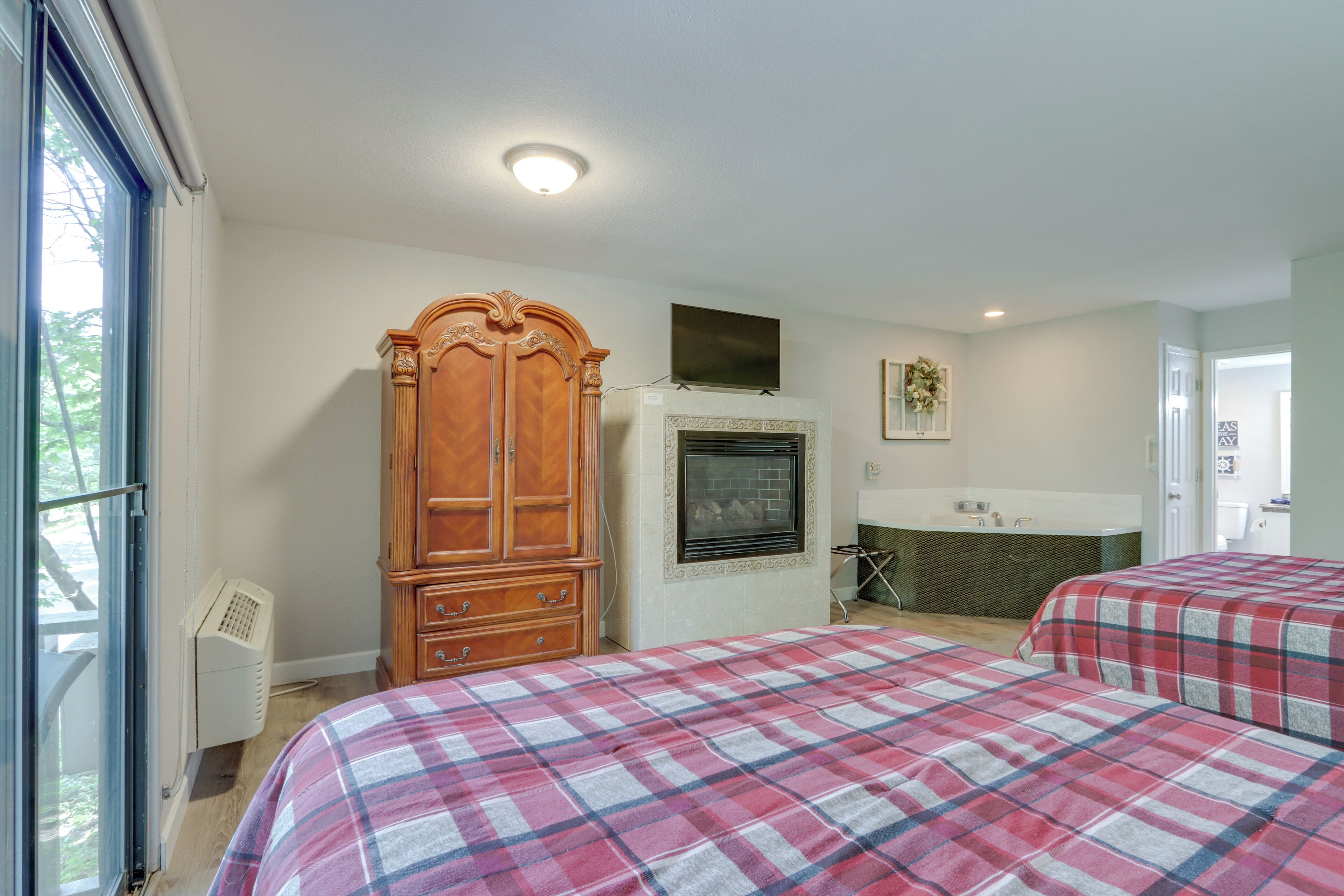 Quarto com duas camas, um guarda-roupa de madeira, lareira e banheiro com banheira.