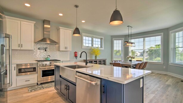 A modern kitchen with stainless steel appliances, a central island, pendant lighting, and large windows. - Gorgeous Newly Built Home: Golf Course View! (Brigantine)
