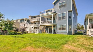 A multi-story residential building with a balcony on the second floor, a covered front porch, and a staircase leading to the upper levels. - Gorgeous Newly Built Home: Golf Course View! (Brigantine)