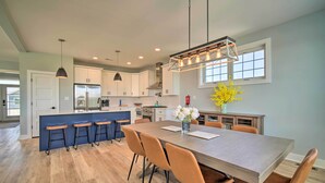 A modern kitchen with a central island, bar stools, and a dining table with chairs. - Gorgeous Newly Built Home: Golf Course View! (Brigantine)