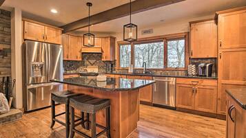 A spacious kitchen with wooden cabinets, a stainless steel refrigerator, and a large island with stools.