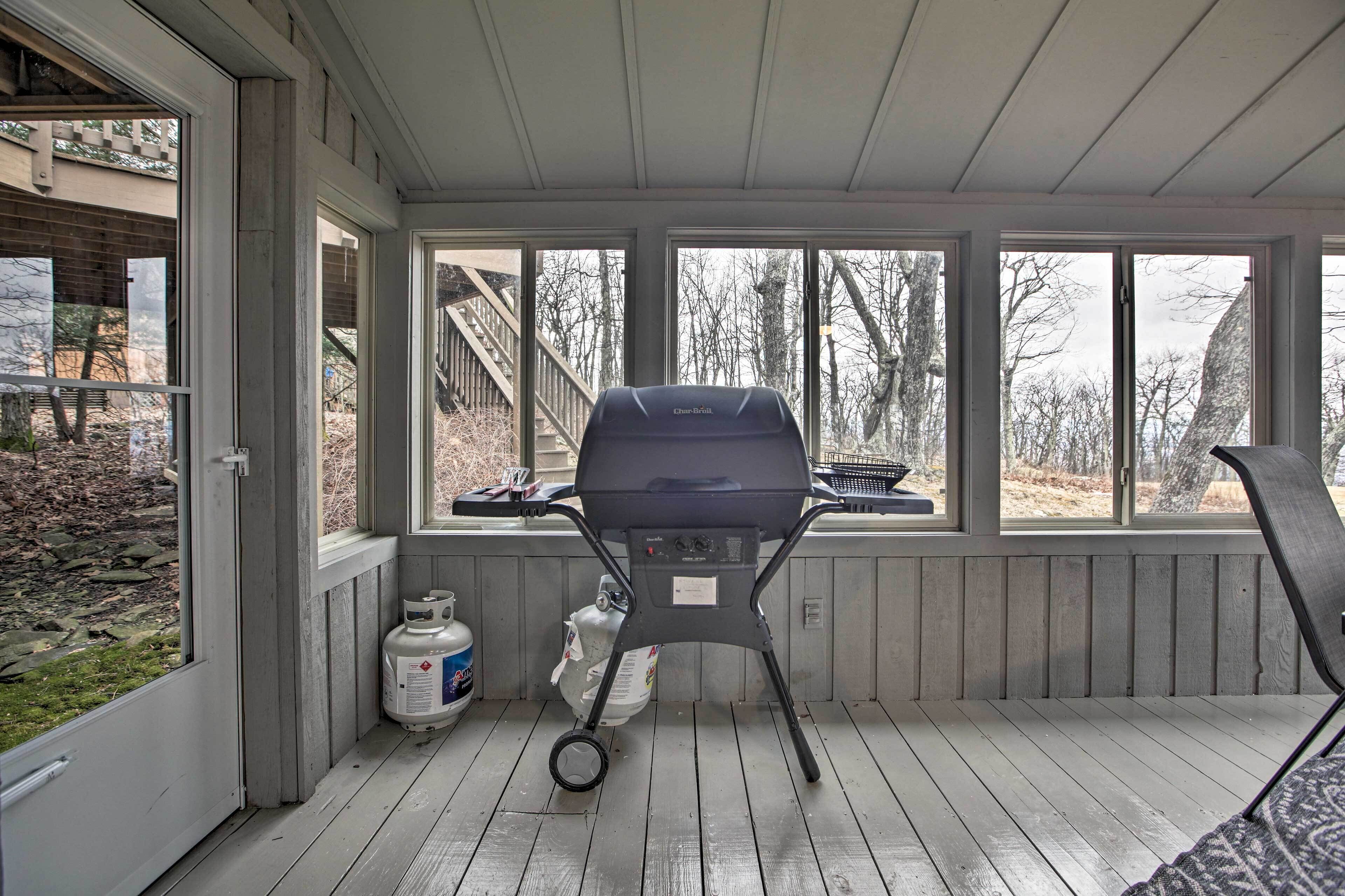 A covered outdoor area with a barbecue grill, gas cylinders, and a view of the surrounding landscape.