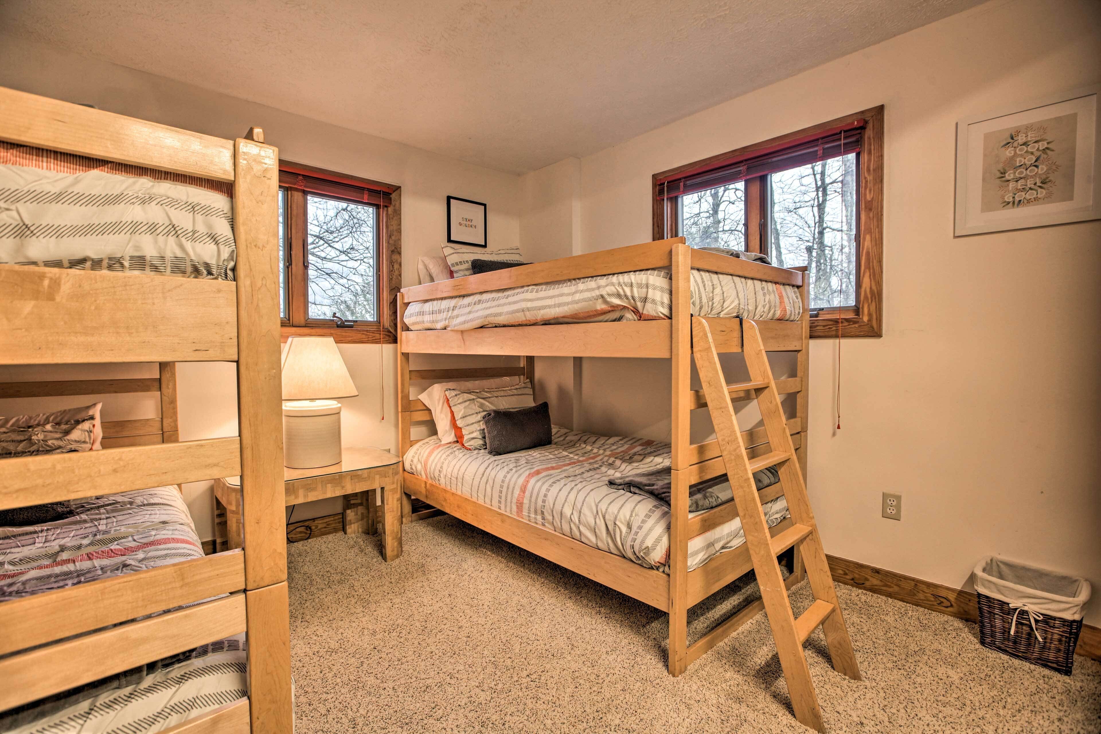 A bunk bed room with a ladder, a bedside table with a lamp, and a framed picture on the wall.