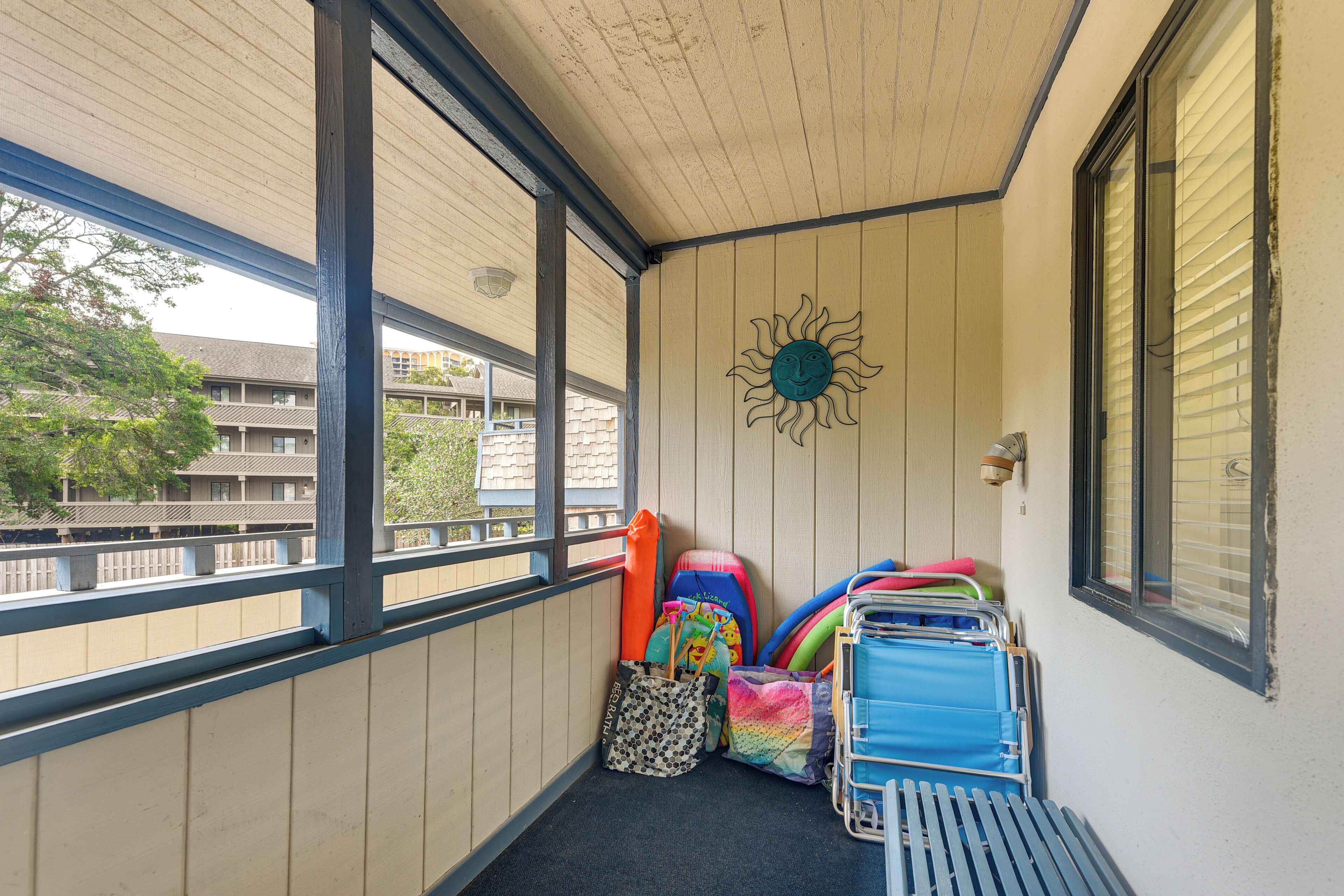 A balcony with a view of buildings, a sun decoration, and various colorful bags and suitcases.