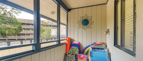 A balcony with a view of buildings, a sun decoration, and various colorful bags and suitcases.