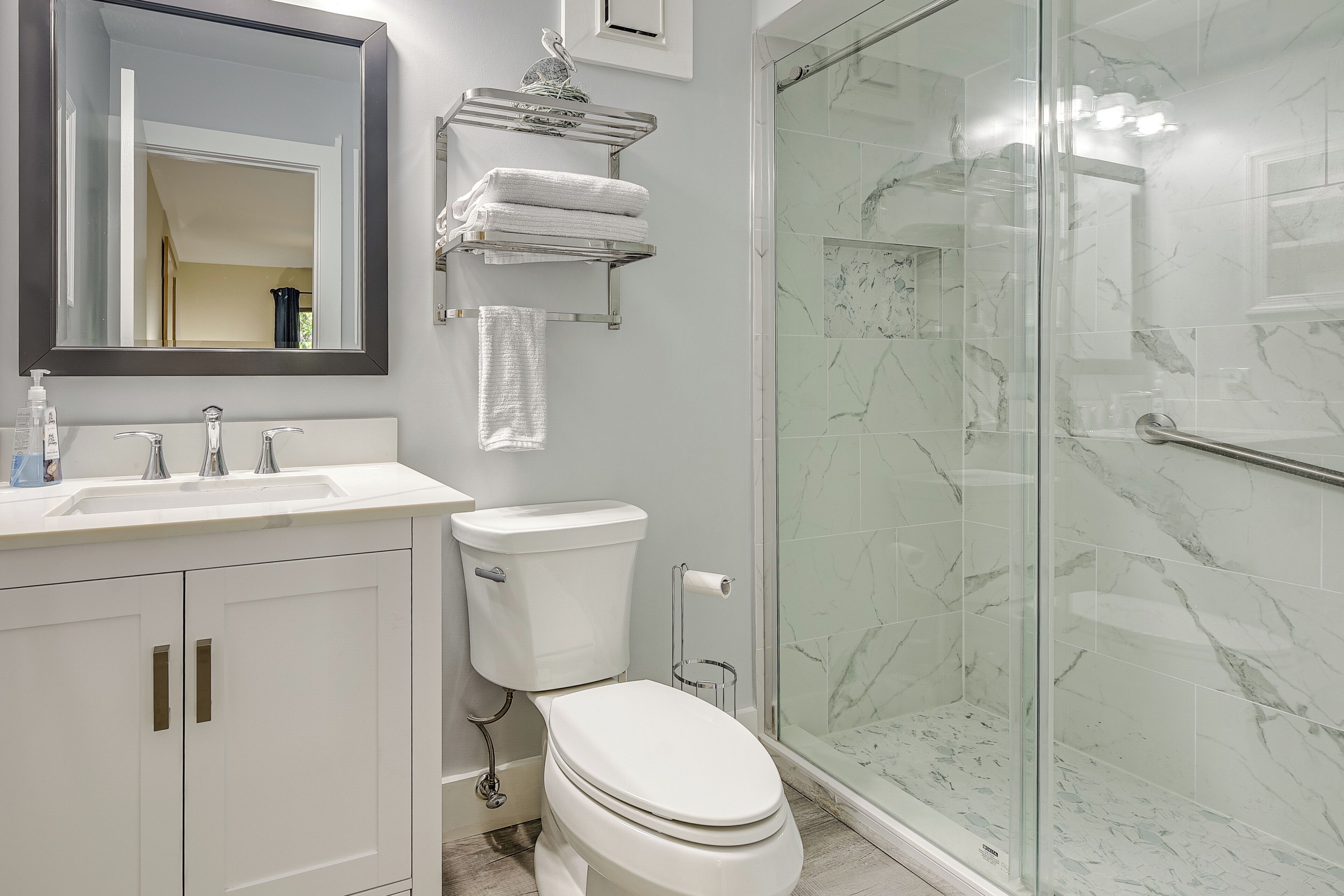 A modern bathroom with a white sink, toilet, and glass-enclosed shower.