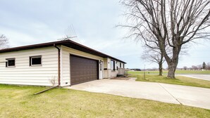 Einbungalow mit Garage, einer kleinen Veranda und einem Baum im Garten.