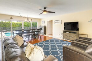 A living room with a leather couch, a patterned rug, a television, and a dining area with a table and chairs. - Riviera Beach Vacation Home w/ Pool: Walk to Beach (Singer Island)