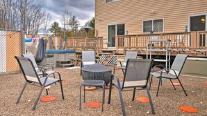 An outdoor patio with a round table and chairs, a covered seating area, and a wooden deck.