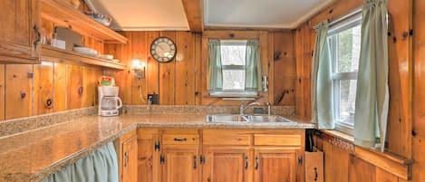 A wooden kitchen with granite countertops, a coffee maker, and a sink.