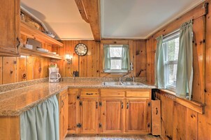 Una cocina de madera con encimeras de granito, una cafetera y un fregadero.
