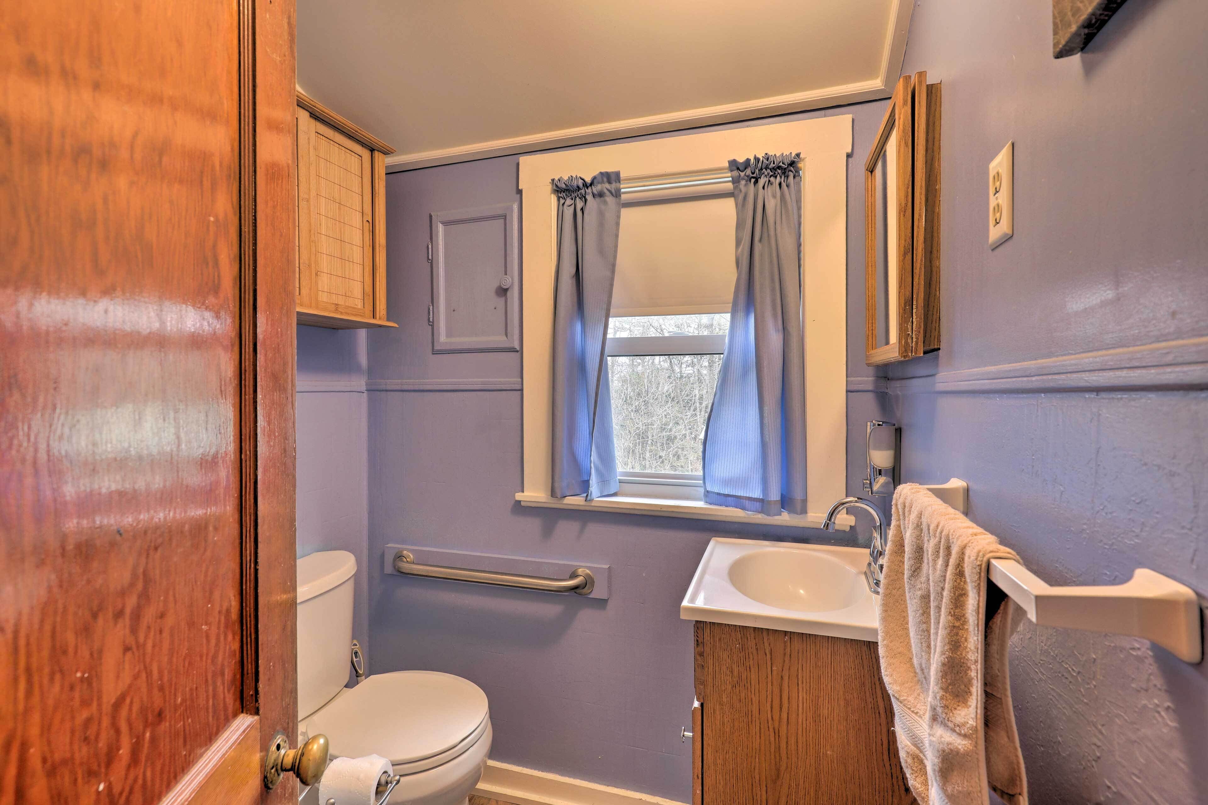 A bathroom with a toilet, sink, and window with curtains.