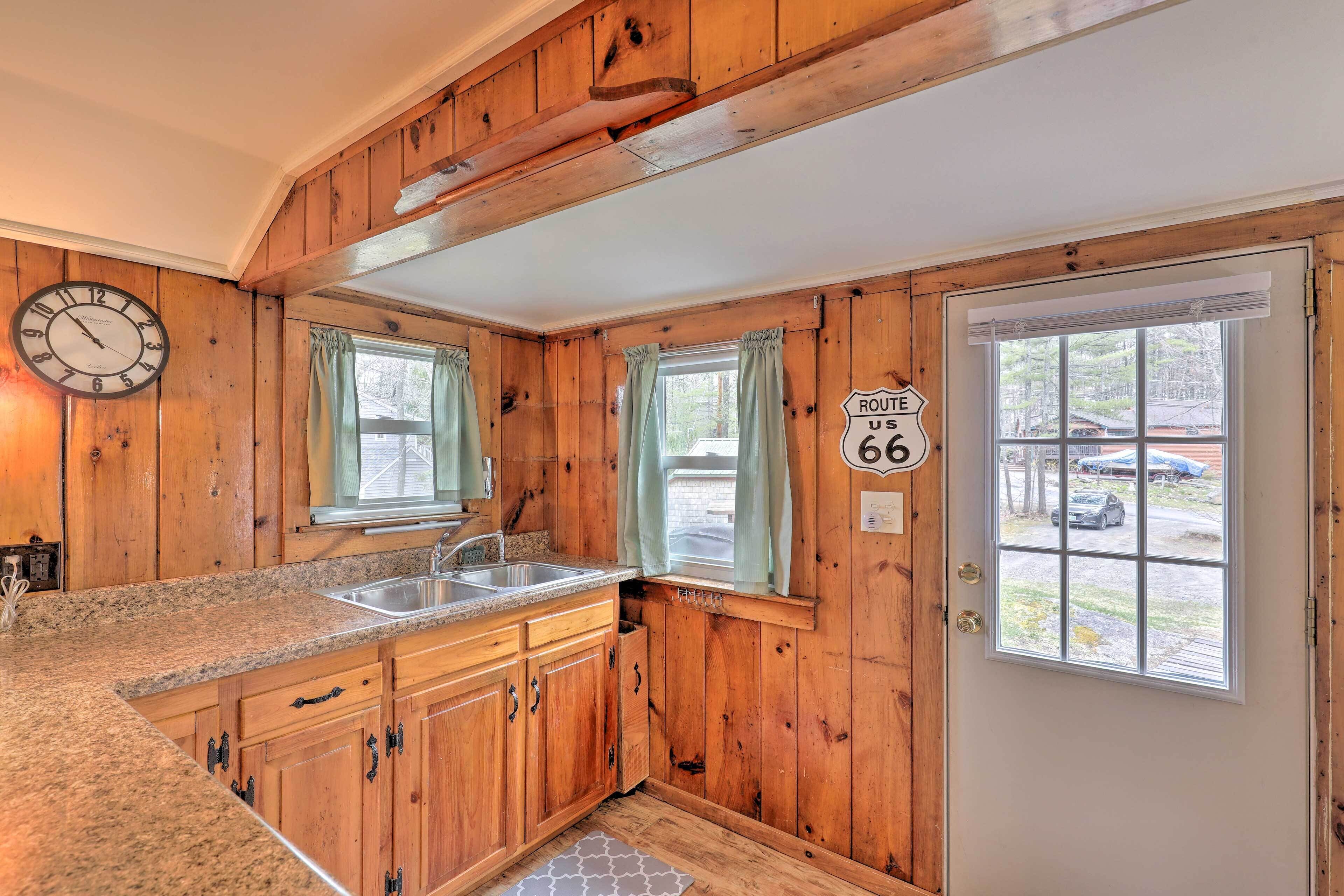 Un intérieur en bois comprenant un espace cuisine, avec un évier, des placards et une horloge.