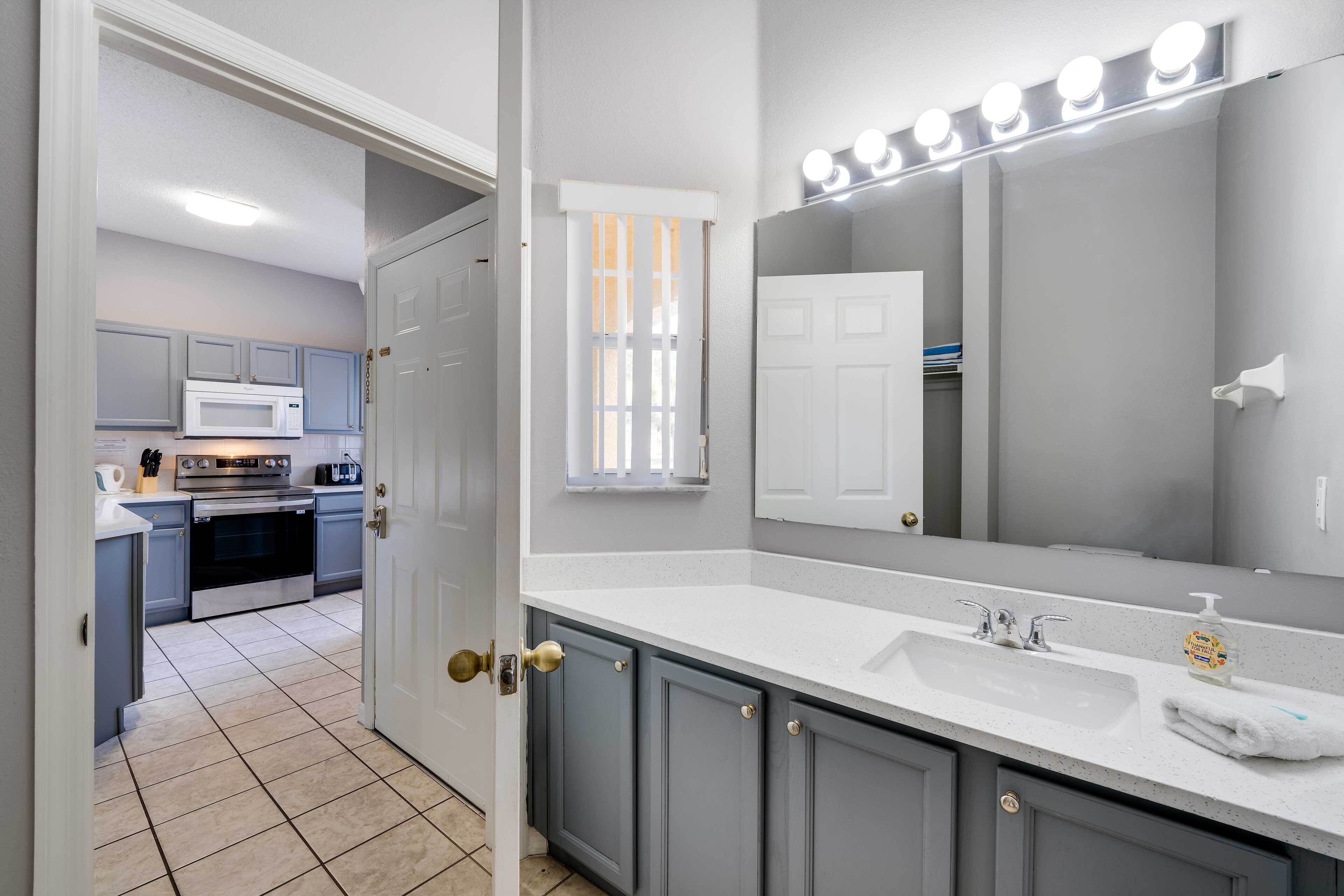 A modern bathroom with a large mirror, vanity, and a sink.