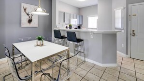 A modern kitchen with grey cabinets, a white countertop, and a hanging light fixture. - Kissimmee Escape ~ 10 Mi to Disney World! (Kissimmee)