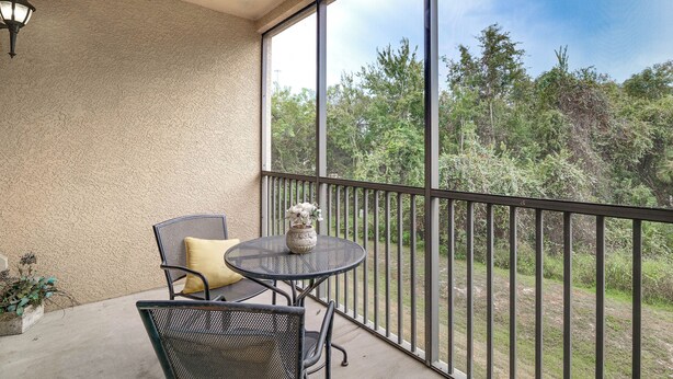Ein Balkon mit Tisch und Stühlen, einem Blumentopf und Blick auf eine bewaldete Landschaft.