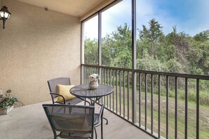 Ein Balkon mit Tisch und Stühlen, einem Blumentopf und Blick auf eine bewaldete Landschaft.