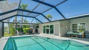 A swimming pool with a glass enclosure, a seating area with a sofa, and a view of palm trees. - Canalfront Home w/ Dock & Pool: 5 Mi to Ft Myers! (North Fort Myers)