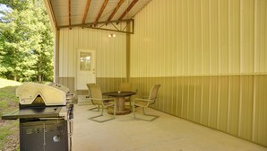 An outdoor patio with a grill, a table, and chairs. - Wooded Gilbertsville Hideaway on Kentucky Lake! (Gilbertsville)