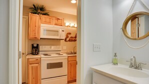 A kitchen with wooden cabinets, a microwave, a stove, and a coffee maker. - Wooded Gilbertsville Hideaway on Kentucky Lake! (Gilbertsville)