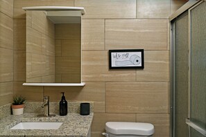 A bathroom with a sink, mirror, toilet, and a framed picture on the wall. - Rare Find Downtown Florence 2 Br (Florence)