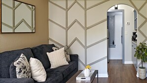 A living room with a dark grey sofa, a coffee table, and a decorative mirror on the wall. - Rare Find Downtown Florence 2 Br (Florence)