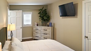 A bedroom with a bed, a dresser, a television, and a window with blinds. - Rare Find Downtown Florence 2 Br (Florence)