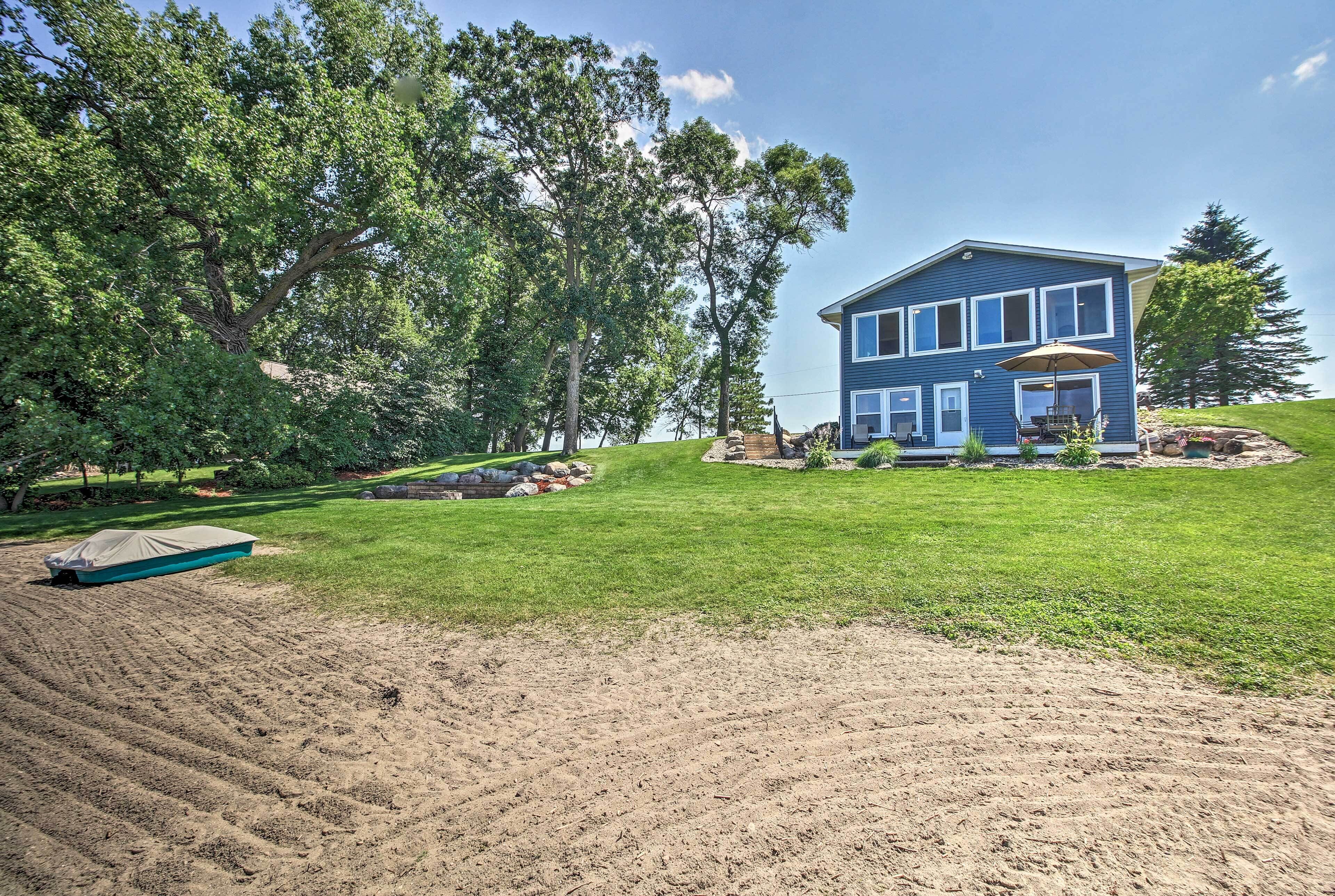 A two-story house with a blue exterior, surrounded by a well-maintained lawn and trees.