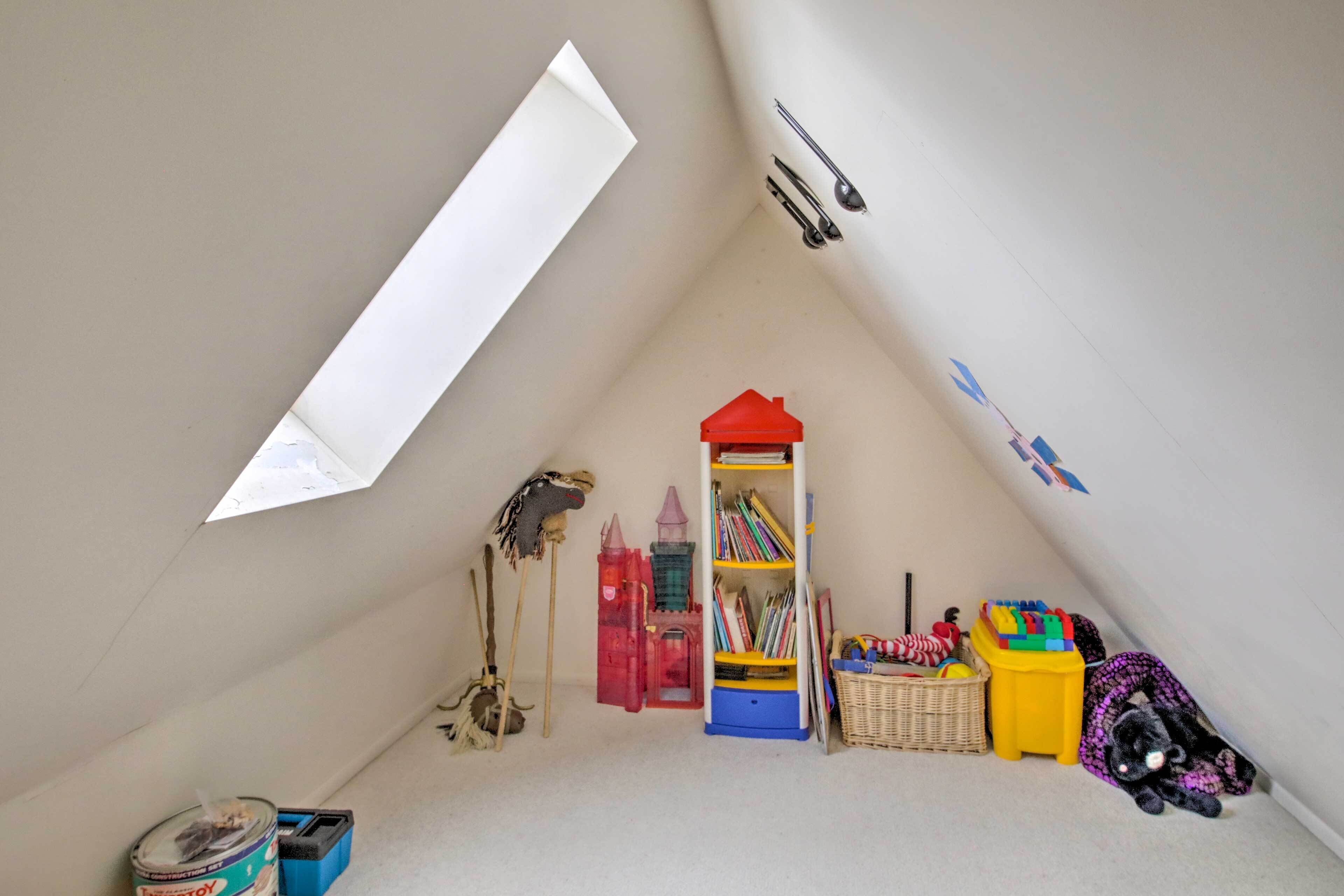 Una stanza da gioco per bambini con soffitto spiovente, una libreria e numerosi giochi.