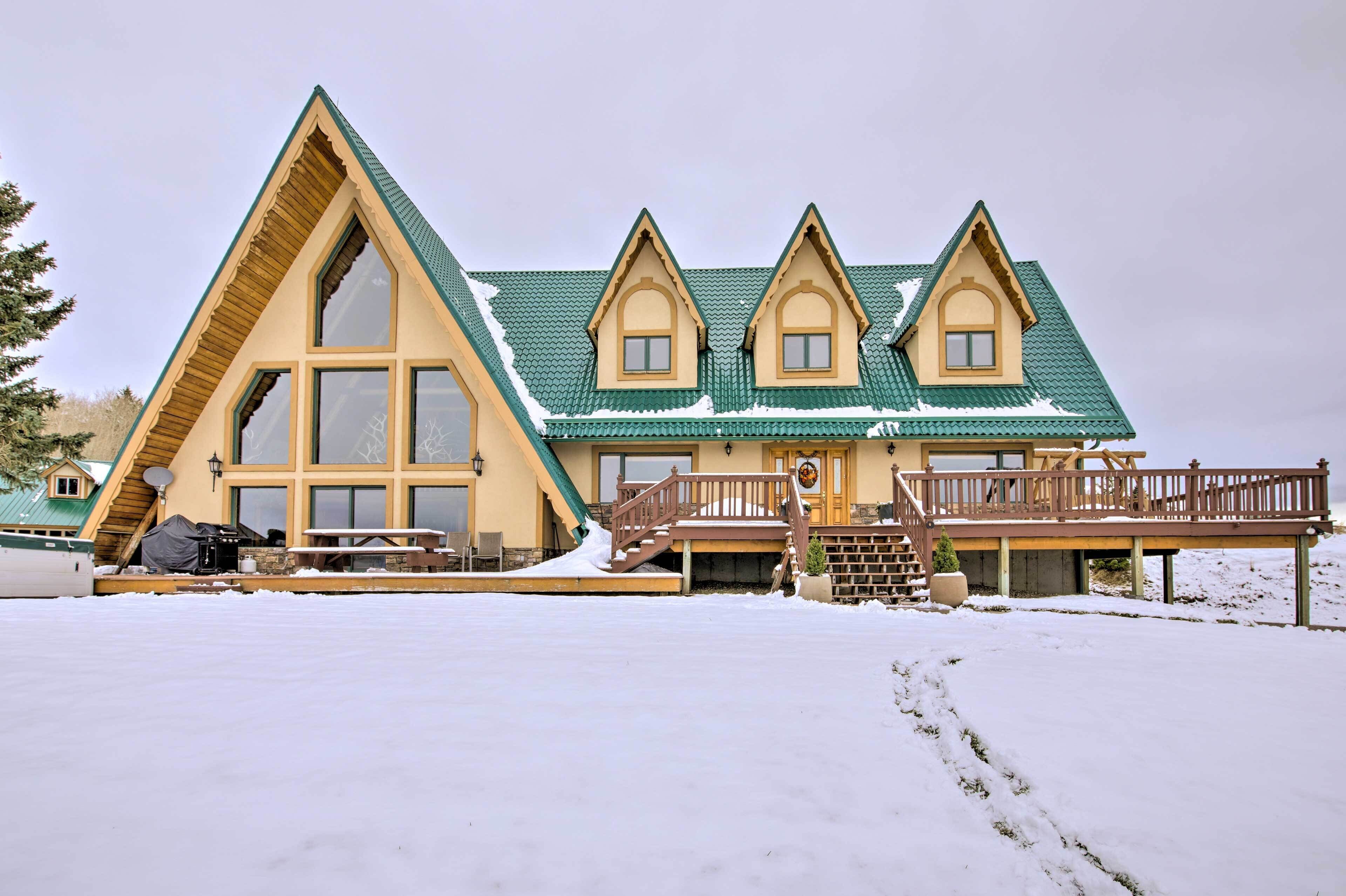 Ein Chalet mit steiler Dachneigung, großen Fenstern und einer Holzterrasse.