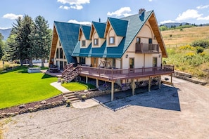A chalet-style building with a steeply pitched roof, a wooden deck, and a stone foundation.