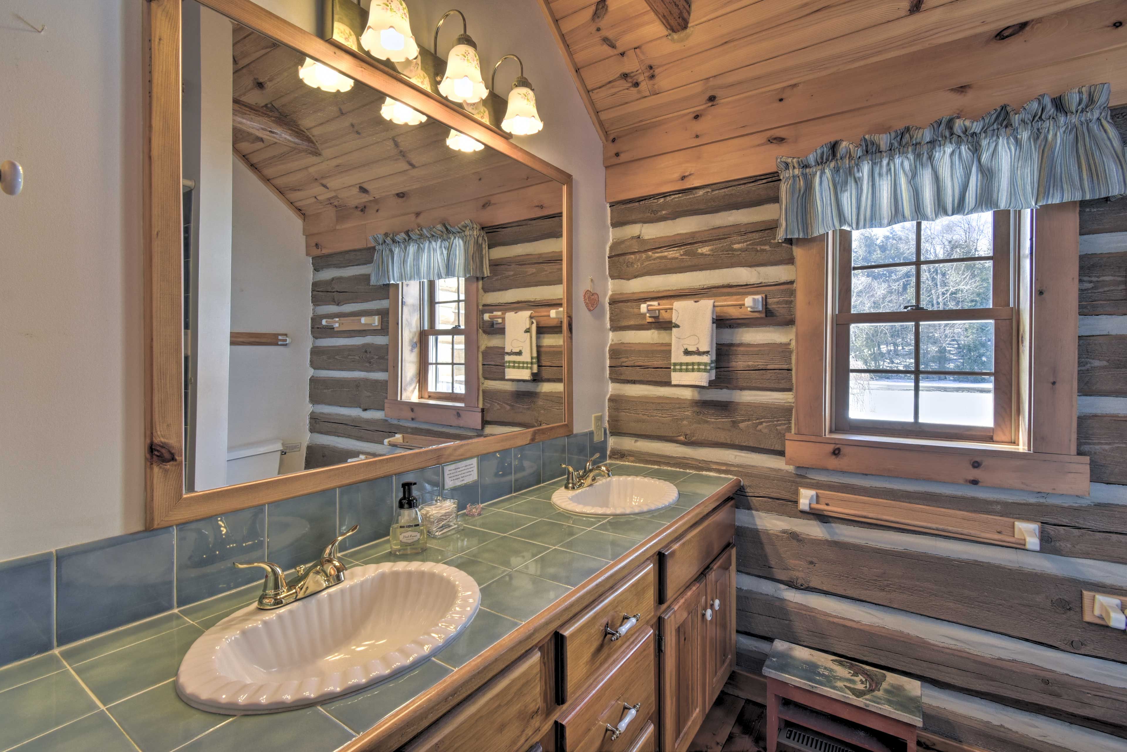 Un baño tipo cabaña con dos lavamanos, paredes de madera y un espejo grande.