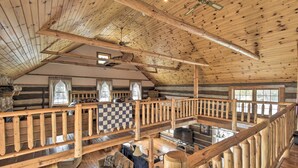 A spacious log cabin with a high ceiling, wooden beams, a checkered floor, and a balcony with a wooden railing. - Soak, Relax & Explore! Walk to Wolf River (White Lake)