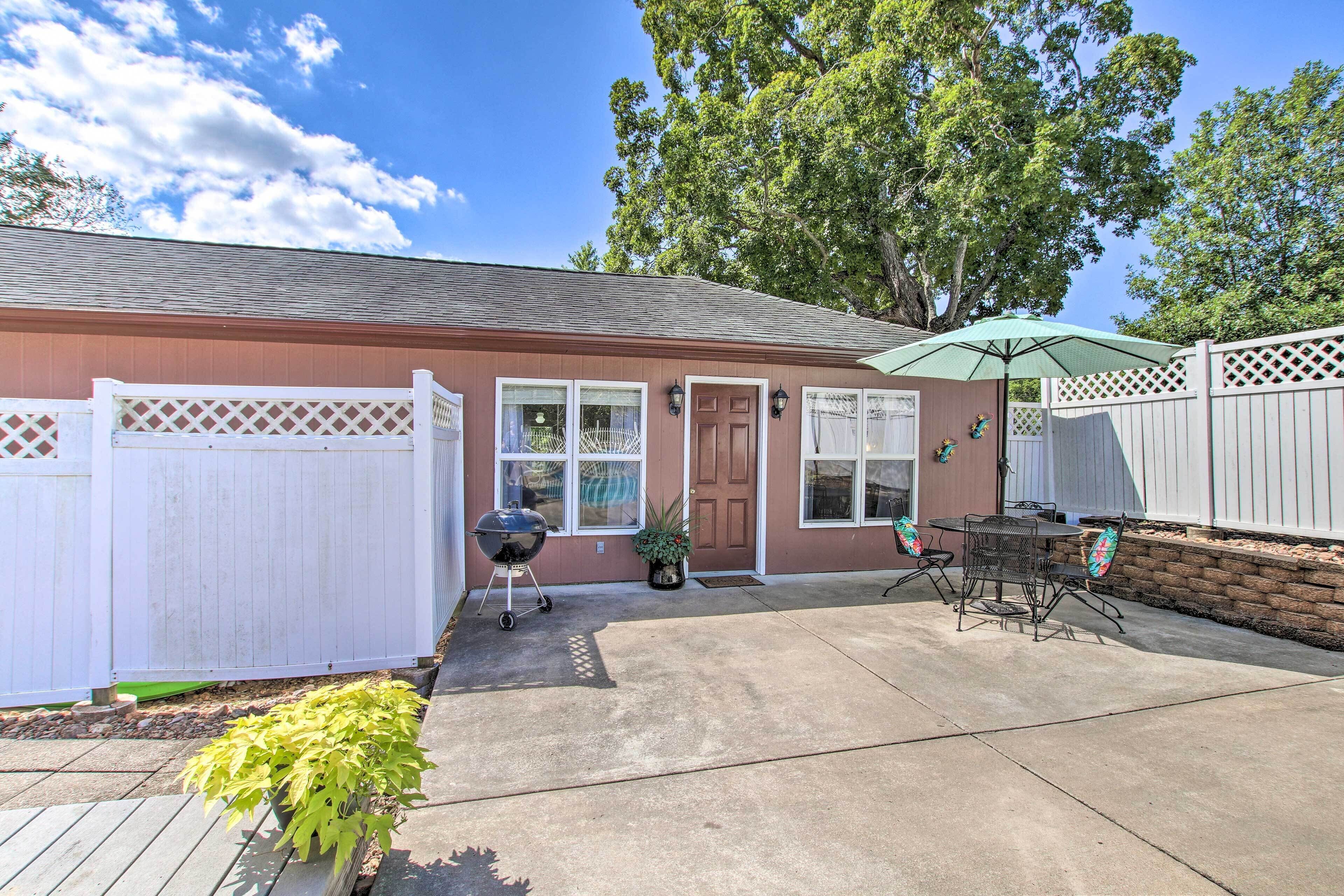 A residential backyard with a barbecue grill, patio furniture, and a white fence.