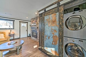 Un salon avec une cheminée, une grande fenêtre et un lave-linge.