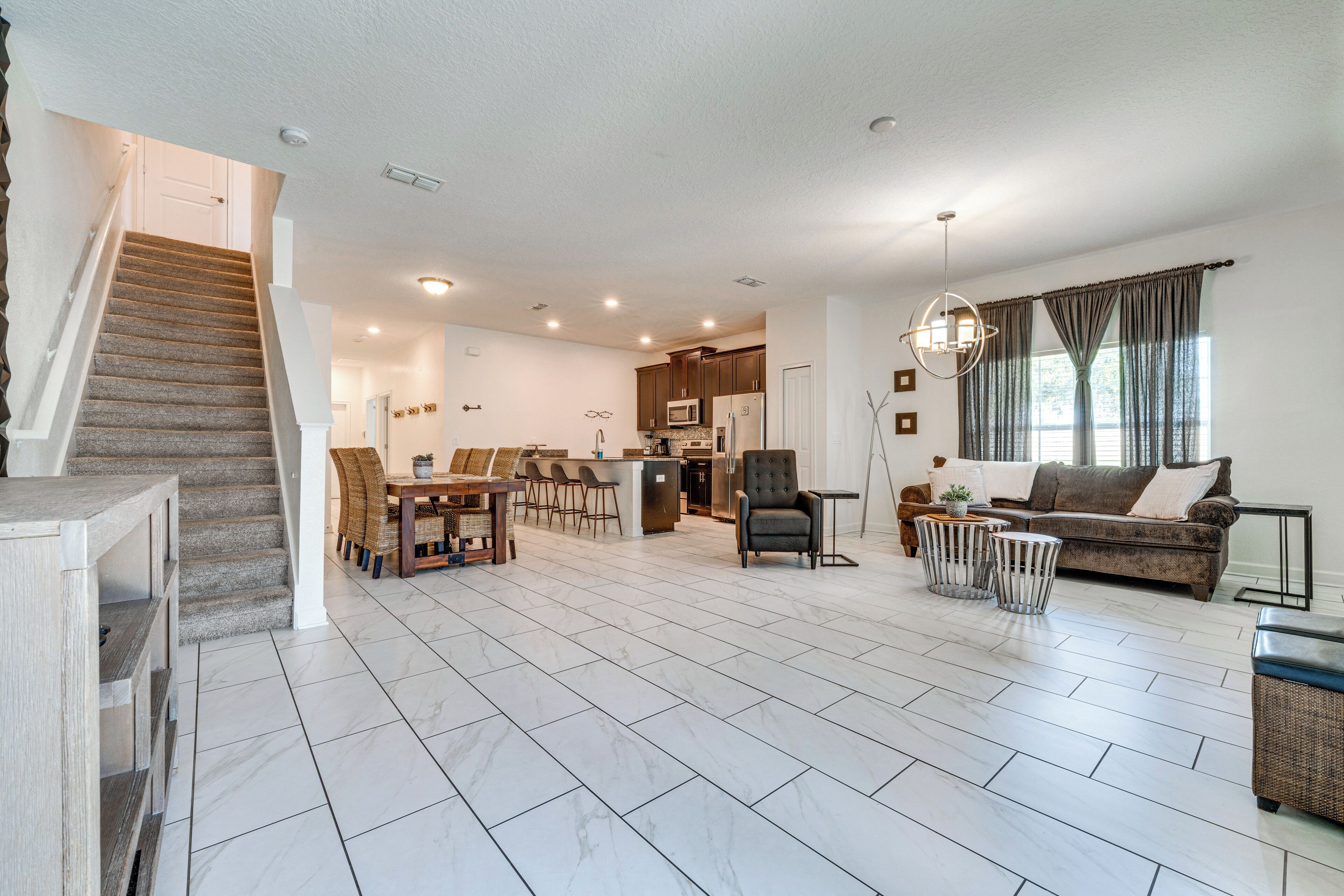 A spacious living area with a kitchen, dining area, and a staircase.