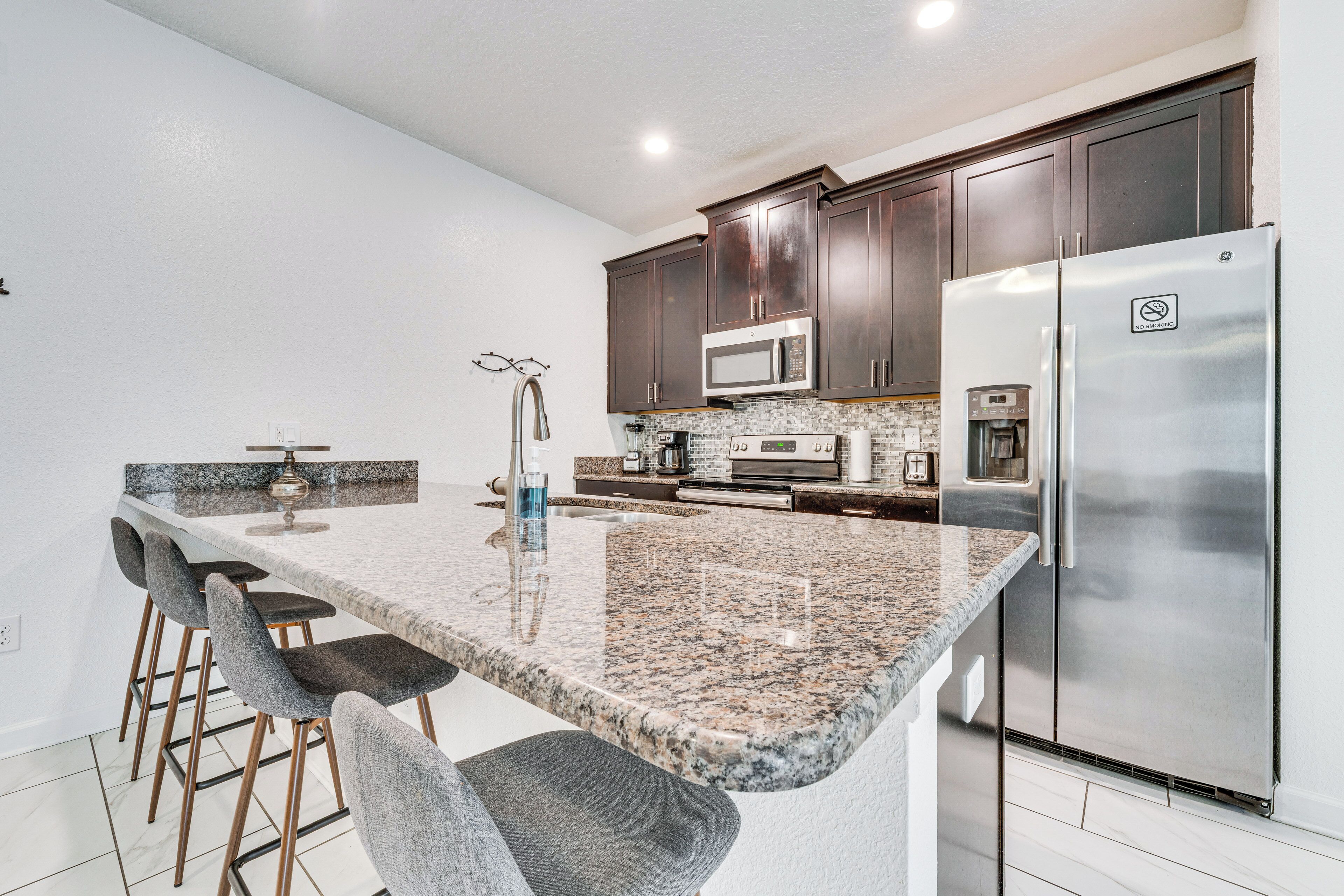 A kitchen with granite countertops, stainless steel appliances, and dark wooden cabinets.