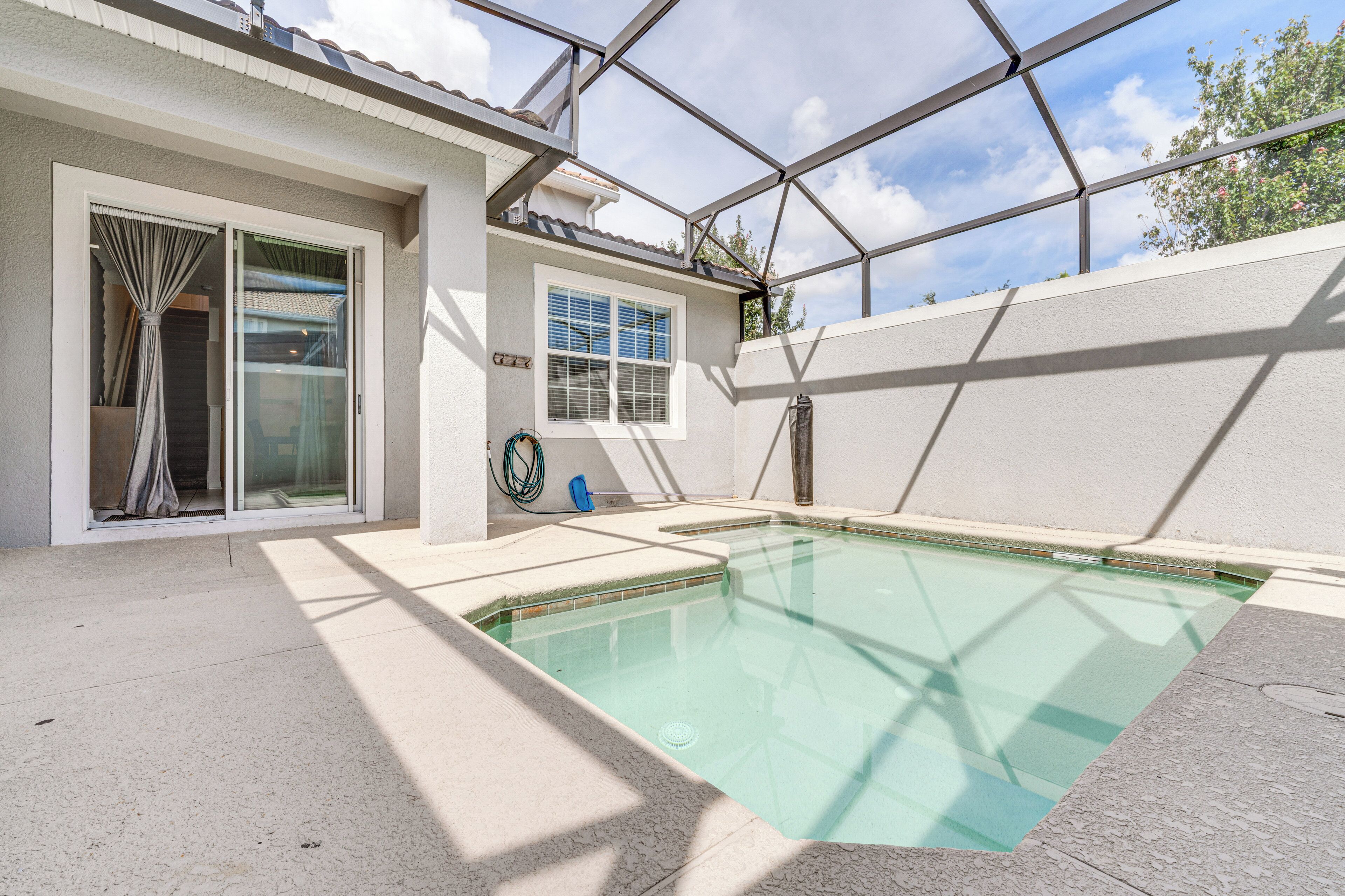 A swimming pool with clear water, surrounded by a covered patio area with a pergola structure.