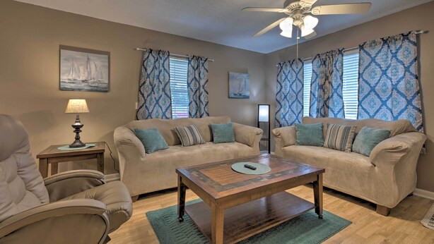 A living room with two beige sofas, a wooden coffee table, a floor lamp, and a ceiling fan. - Breezy Gulfport Getaway < 1 Mile to Beach + Casino (Gulfport)