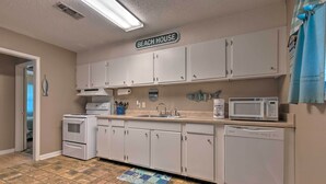 A kitchen with white cabinets, a microwave, a dishwasher, and a sign that reads "BEACH HOUSE". - Breezy Gulfport Getaway < 1 Mile to Beach + Casino (Gulfport)