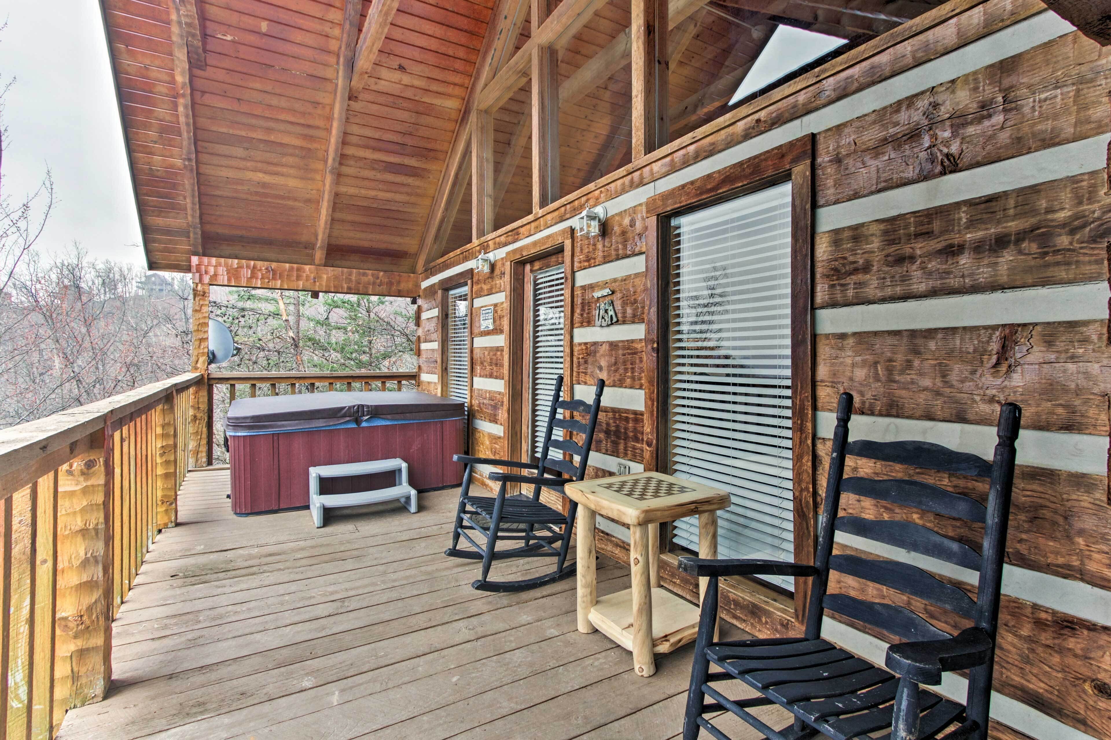 Eine Holzterrasse mit Whirlpool, Schaukelstühlen und einem kleinen Tisch.