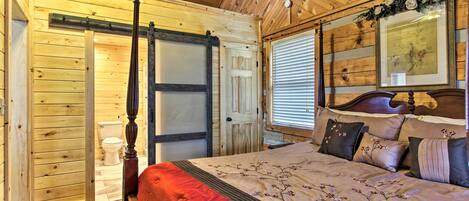 A wooden-paneled bedroom with a four-poster bed, a sliding door, and a framed picture above the bed.