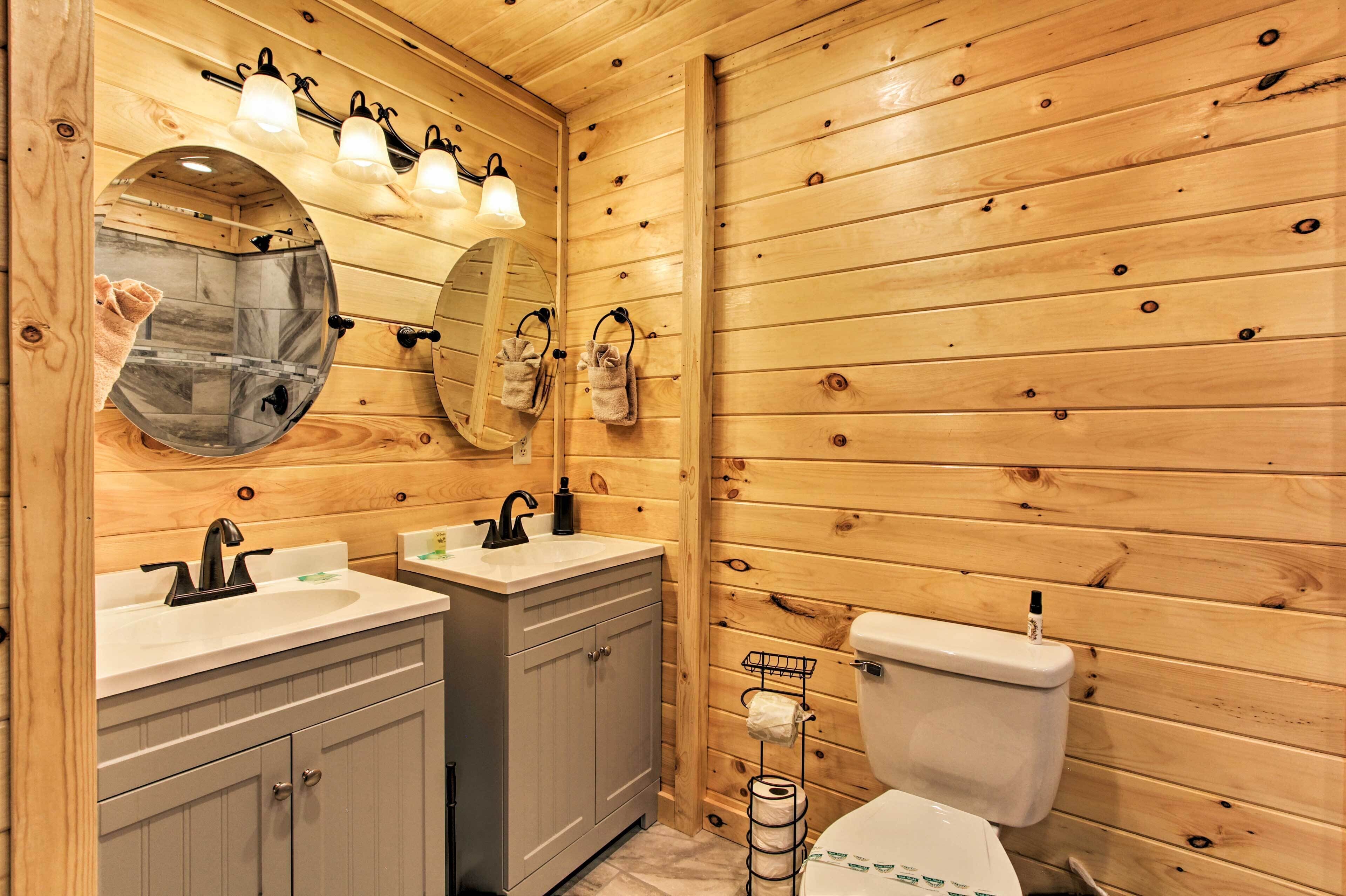 Un baño con paneles de madera, dos lavamanos, un inodoro y un espejo con iluminación.