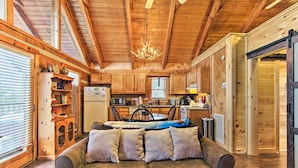 A cozy cabin interior with a wooden ceiling, a dining area, and a sofa with cushions. - Sevierville Cabin w/ Private Hot Tub & Fireplace! (Sevierville)