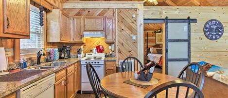 A wooden interior with a kitchen, dining area, and a clock on the wall.