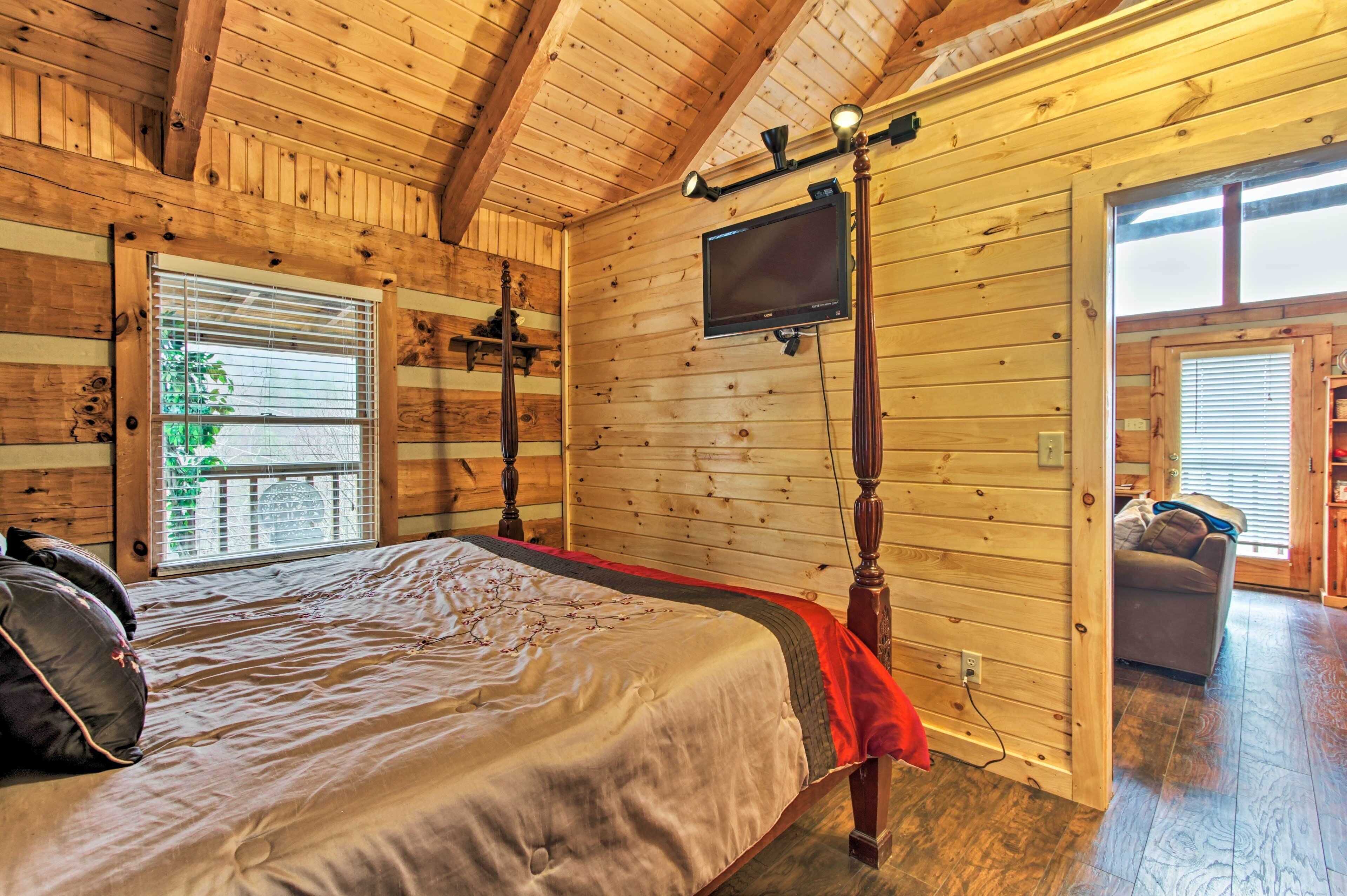 Un dormitorio de cabaña de madera con una cama, un televisor y una ventana.