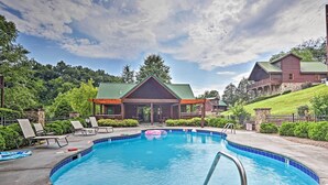 A pool area with lounge chairs, a pool, and a building with a green roof. - 3 Mi to Dollywood: Hot Tub Hideaway in Smoky Mtns (Sevierville)