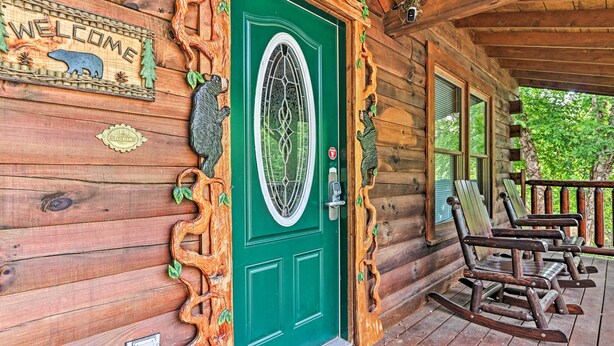 A wooden cabin with a green door, a welcome sign, and rocking chairs on the porch. - 3 Mi to Dollywood: Hot Tub Hideaway in Smoky Mtns (Sevierville)